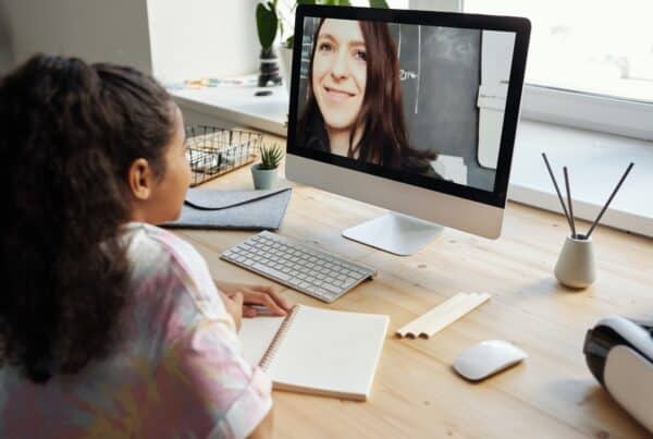 E-learning in action - a girl sits at a Mac with a teacher on screen