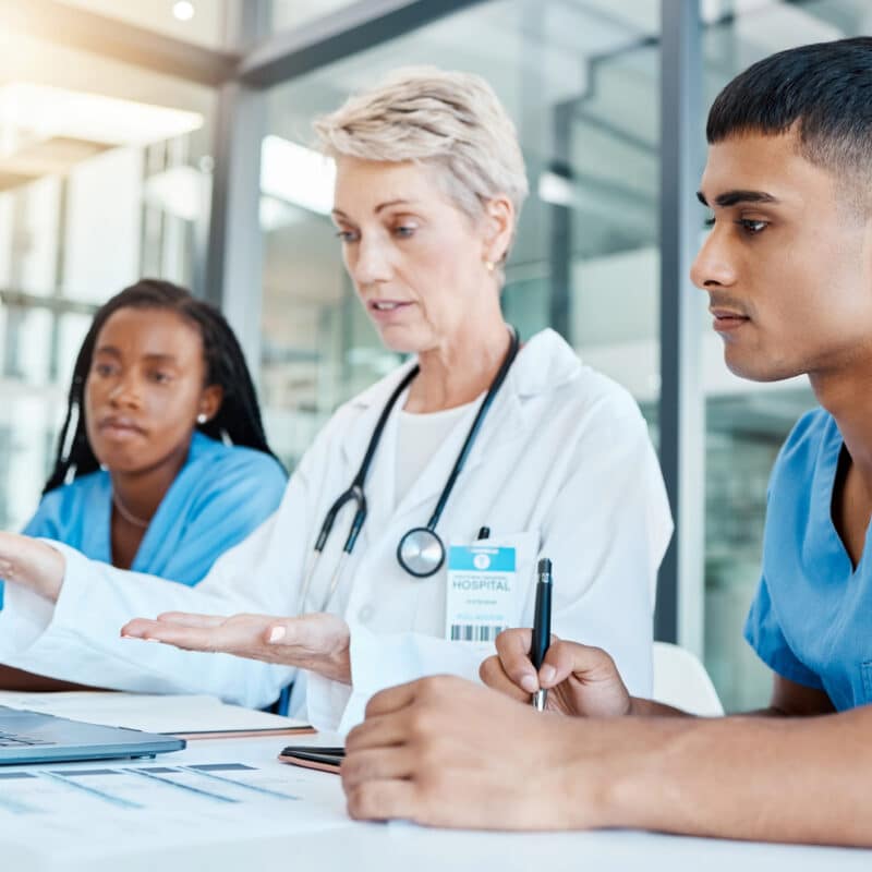 Healthcare training. A senior medical professional runs through a training module with two junior medical professionals