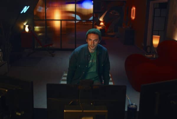 Still image from Hello Stranger. A man sits in a low-lit room looking at a computer. He looks worried.